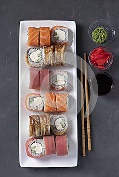 Sushi set with salmon, tuna and smoked eel with philadelphia cheese on white plate on gray background. Served with soy sauce,