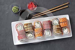 Sushi set with salmon, tuna and smoked eel with philadelphia cheese on white plate on gray background. Served with soy sauce,