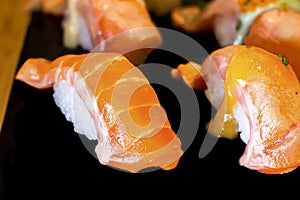 Sushi Set Sashimi and sushi rolls served on black stone slate.