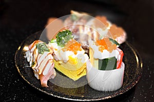 Sushi Set Sashimi and sushi rolls served on black stone slate.
