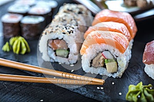 Sushi Set sashimi and sushi rolls served on stone slate.