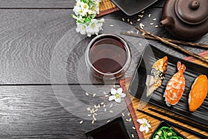 Sushi set sashimi and sushi rolls and white flowers on dark background