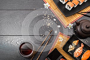 Sushi set sashimi and sushi rolls and white flowers on dark background