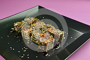 Sushi set served on a black square plate over bright pink background. Traditional Japanese cuisine, sushi rolls close up