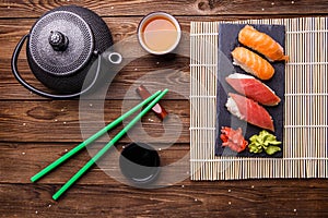 Sushi Set served on gray stone slate with soy sauce, grey teapot and cup of tea