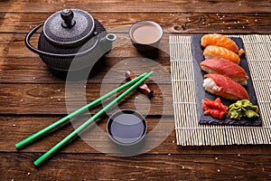 Sushi Set served on gray stone slate with soy sauce, grey teapot and cup of tea