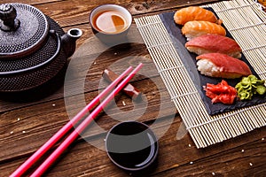 Sushi Set served on gray stone slate with soy sauce, grey teapot and cup of tea