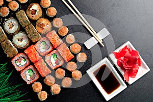 Sushi set served on a stone slate on a dark background. Sushi rolls with salmon, tuna, cucumber, baked, wasabi, soy sauce and