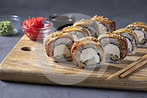 Sushi set with smoked eel and philadelphia cheese on wooden board on gray background. Healthy food