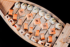Sushi set in a wooden boat on a black background