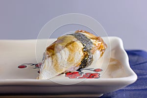 Sushi from smoked eel one on a square dish with a red pattern