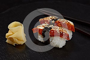 Sushi with smoked eel and sesame seeds on a black background. Japanese dish Unagi sushi.