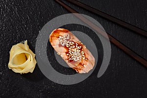 Sushi with smoked eel and sesame seeds on a black background. Japanese dish Unagi sushi.