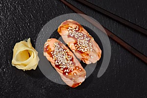 Sushi with smoked eel and sesame seeds on a black background. Japanese dish Unagi sushi.