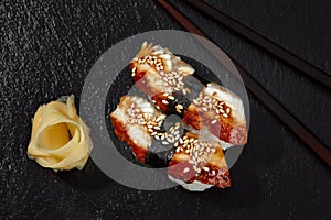 Sushi with smoked eel and sesame seeds on a black background. Japanese dish Unagi sushi.