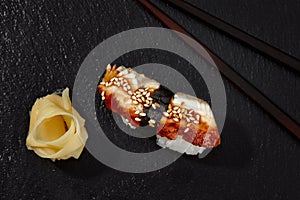 Sushi with smoked eel and sesame seeds on a black background. Japanese dish Unagi sushi.