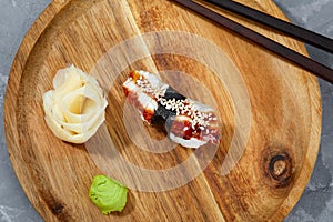 Sushi with smoked eel and sesame seeds on a wooden board. Japanese dish Unagi sushi.