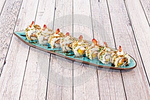 Sushi uramaki dragon roll with shrimp in tempura, pieces of ripe mango