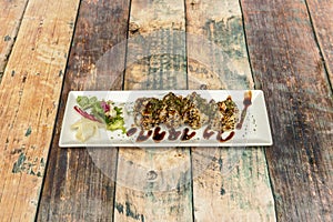 Sushi uramaki dragon roll stuffed with fried prawns in tempura with soy sauce,