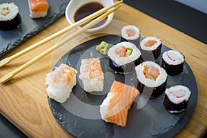 Sushi on a wooden table on black slate plate with soy sauce and