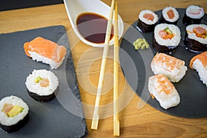 Sushi on a wooden table on black slate plate with soy sauce and