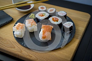 Sushi on a wooden table on black slate plate with soy sauce and