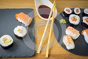 Sushi on a wooden table on black slate plate with soy sauce and