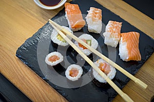 Sushi on a wooden table on black slate plate with soy sauce and