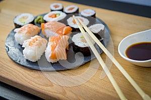 Sushi on a wooden table on black slate plate with soy sauce and