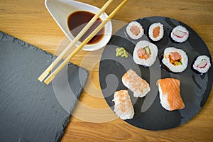 Sushi on a wooden table on black slate plate with soy sauce and