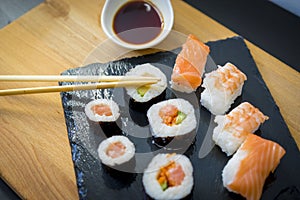 Sushi on a wooden table on black slate plate with soy sauce and