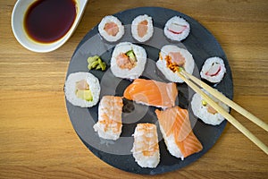 Sushi on a wooden table on black slate plate with soy sauce and