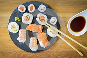 Sushi on a wooden table on black slate plate with soy sauce and