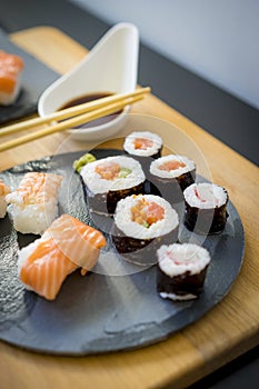 Sushi on a wooden table on black slate plate with soy sauce and