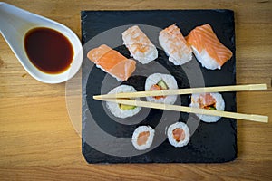 Sushi on a wooden table on black slate plate with soy sauce and