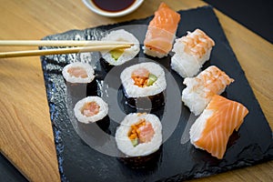 Sushi on a wooden table on black slate plate with soy sauce and