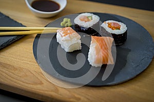 Sushi on a wooden table on black slate plate with soy sauce and