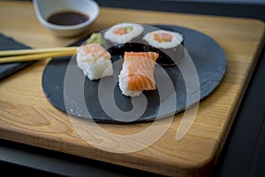 Sushi on a wooden table on black slate plate with soy sauce and