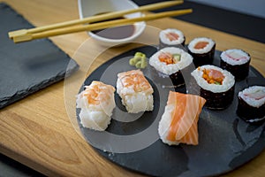 Sushi on a wooden table on black slate plate with soy sauce and