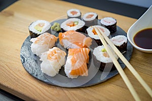 Sushi on a wooden table on black slate plate with soy sauce and