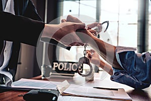 Suspect with handcuffs being interviewed in interrogation room by Police officer, Criminal law concept