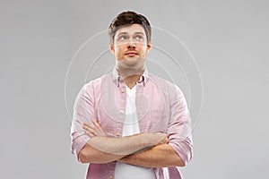 Suspecting young man with crossed hands looking up photo