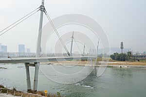 Suspended beam bridge over river in light winter mist