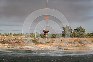 Suspended bucket loaded with water attached to helicopter