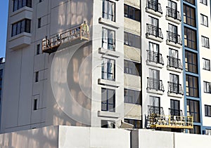 Suspended construction cradle on the background facade of the building. Mobile scaffolding platform for construction work at