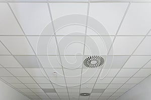 A suspended panel ceiling seen in perspective in a narrow room.