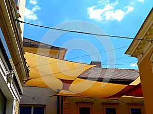 Suspended sun protection awning or tent of cotton fabric stretched over street in old European town