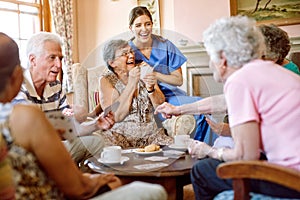 The suspense keeps the game exciting. Shot of a group of happy seniors playing a card game in their retirement home