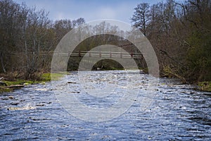 Suspension bridge on the fast-flowing Pirita river on a cloudy spring day