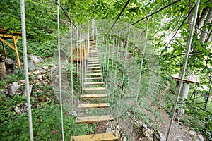 suspension bridge with a ladder in a rope park as a concept of adventure and activity